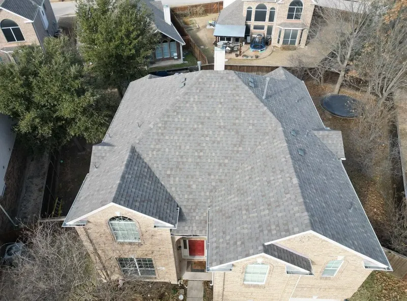A two-story brick home with a gray shingle roof, seen from above