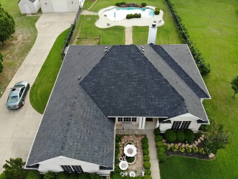 A one-story home with a new dark shingle roof beside a backyard pool