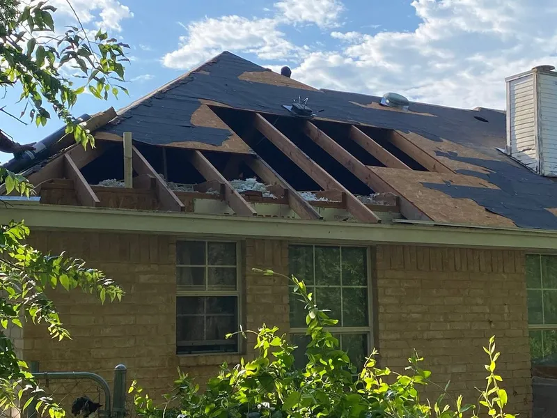 An old roof stripped down to the rafters on a brick home during a roof replacement